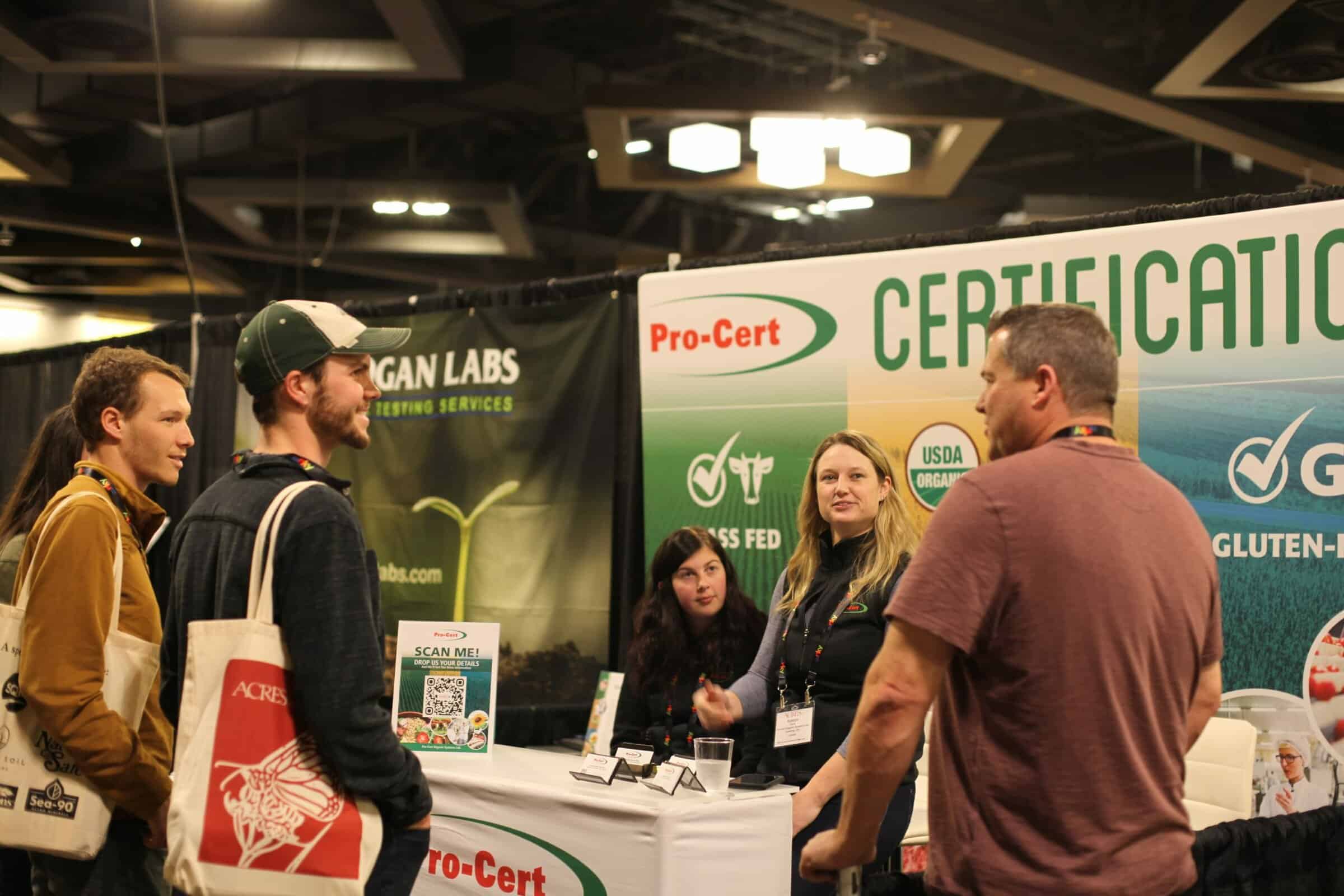 attendees stop to talk at an Eco-Ag trade show booth